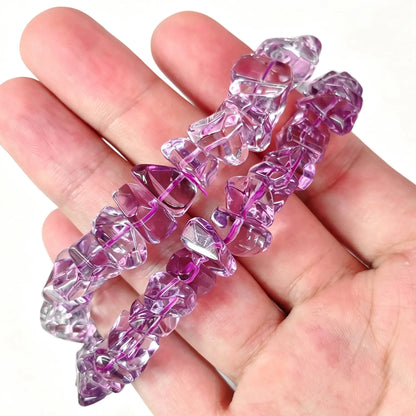 Main view of stacked high clarity amethyst freeform chip bracelets resting on open palm showing bright purple transparency