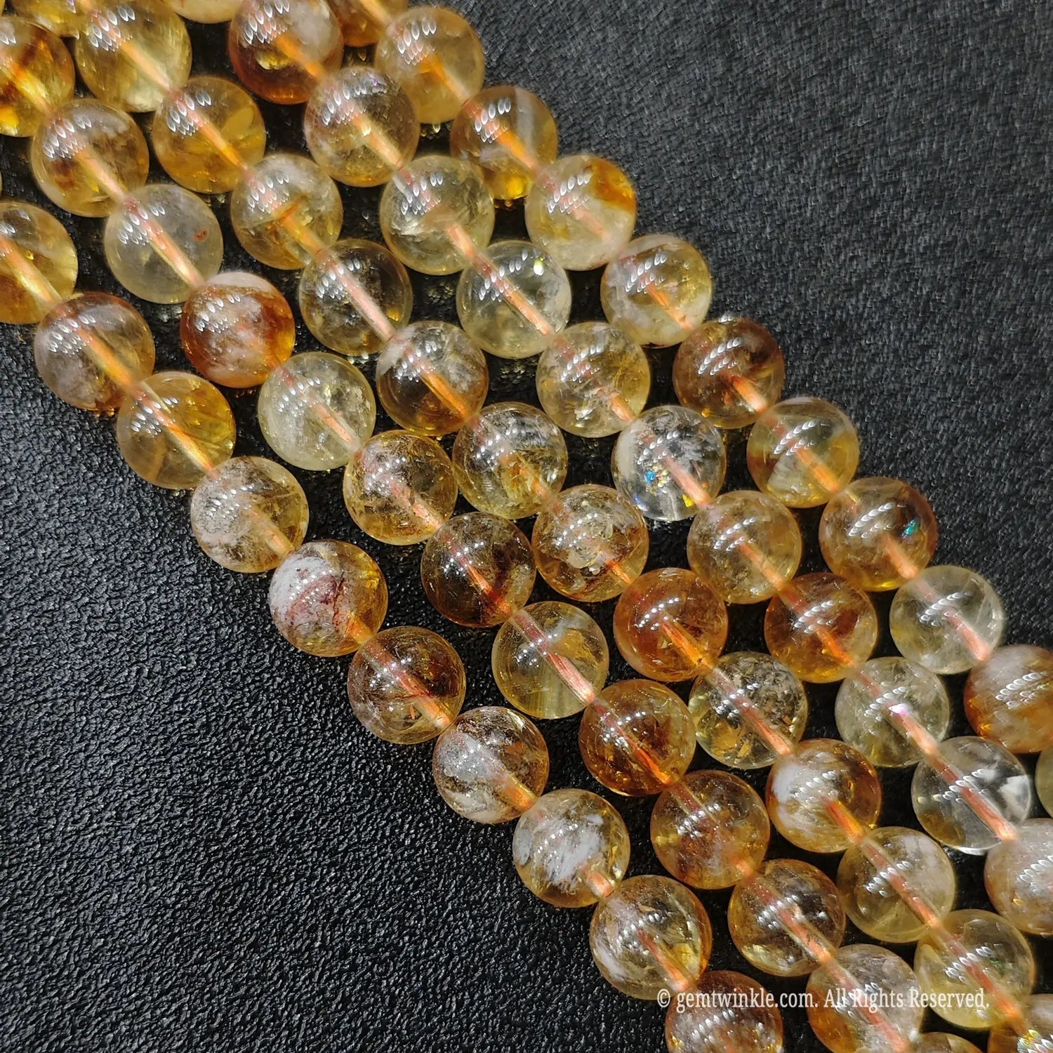 Four neat rows of premium high transparency golden citrine strands showcasing distinct inner tower inclusion structures