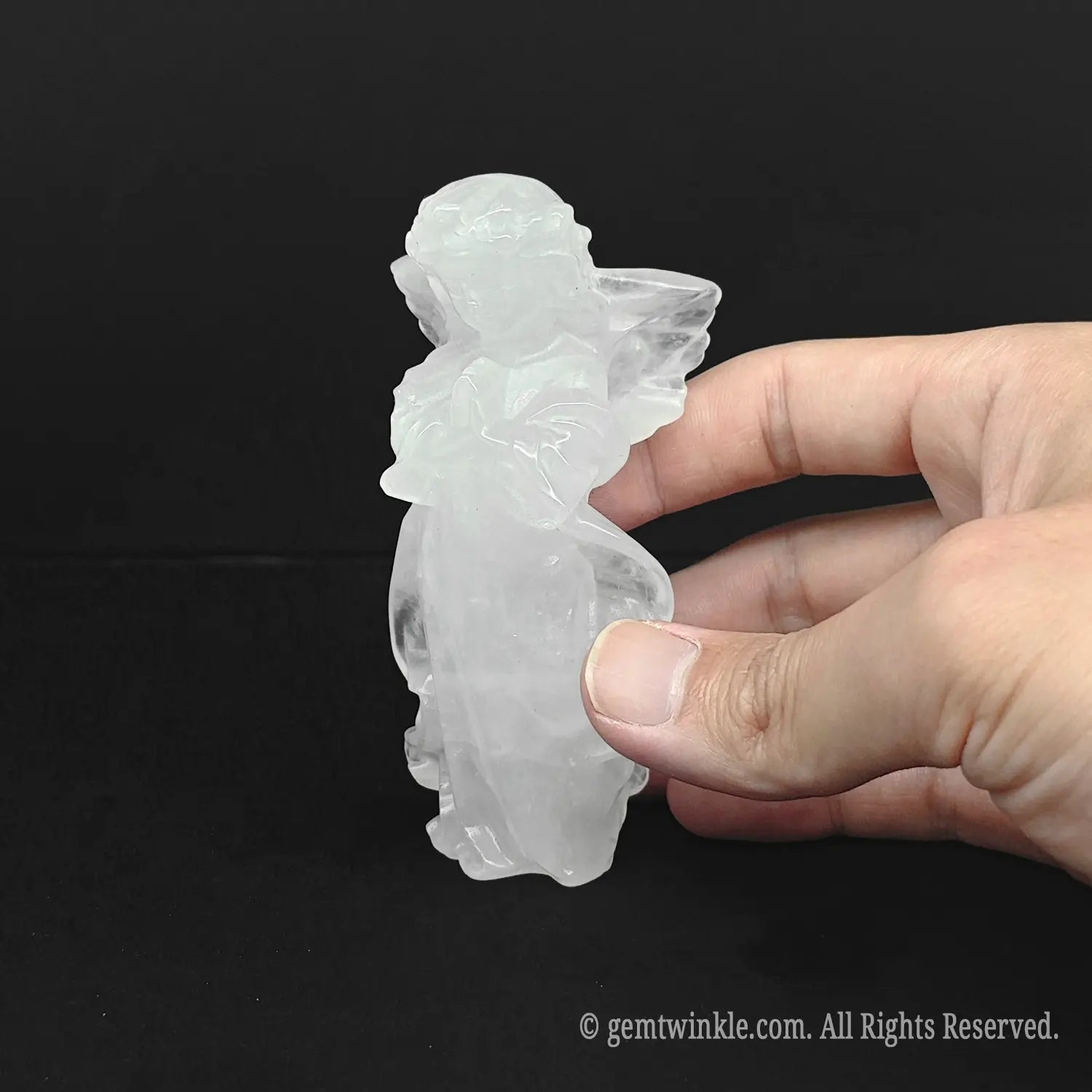 Hand holding an approx 10cm natural milky snow quartz guardian angel carving to display physical scale and calming room aesthetic for wholesale buyers