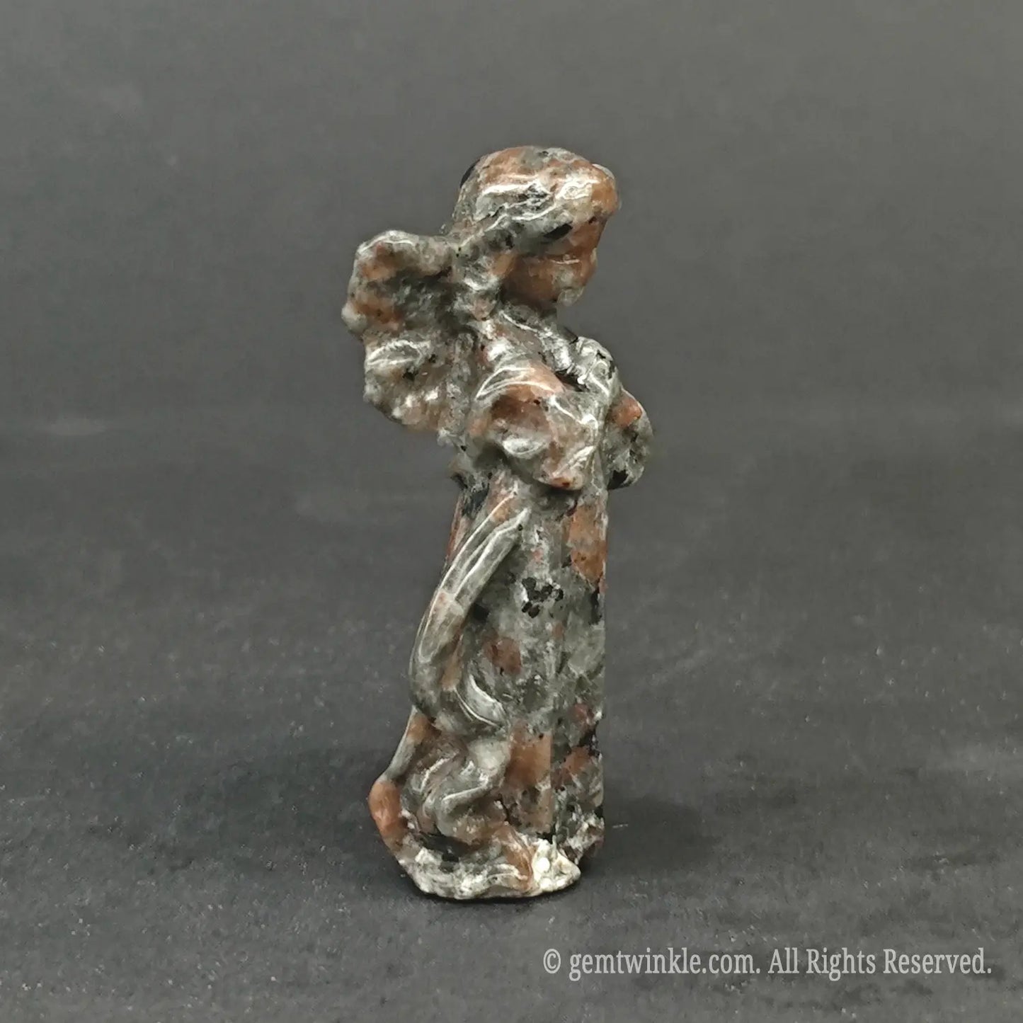 Hand holding a natural mottled granite guardian angel carving to showcase actual physical sizes and earthy stone finish for wholesale buyers