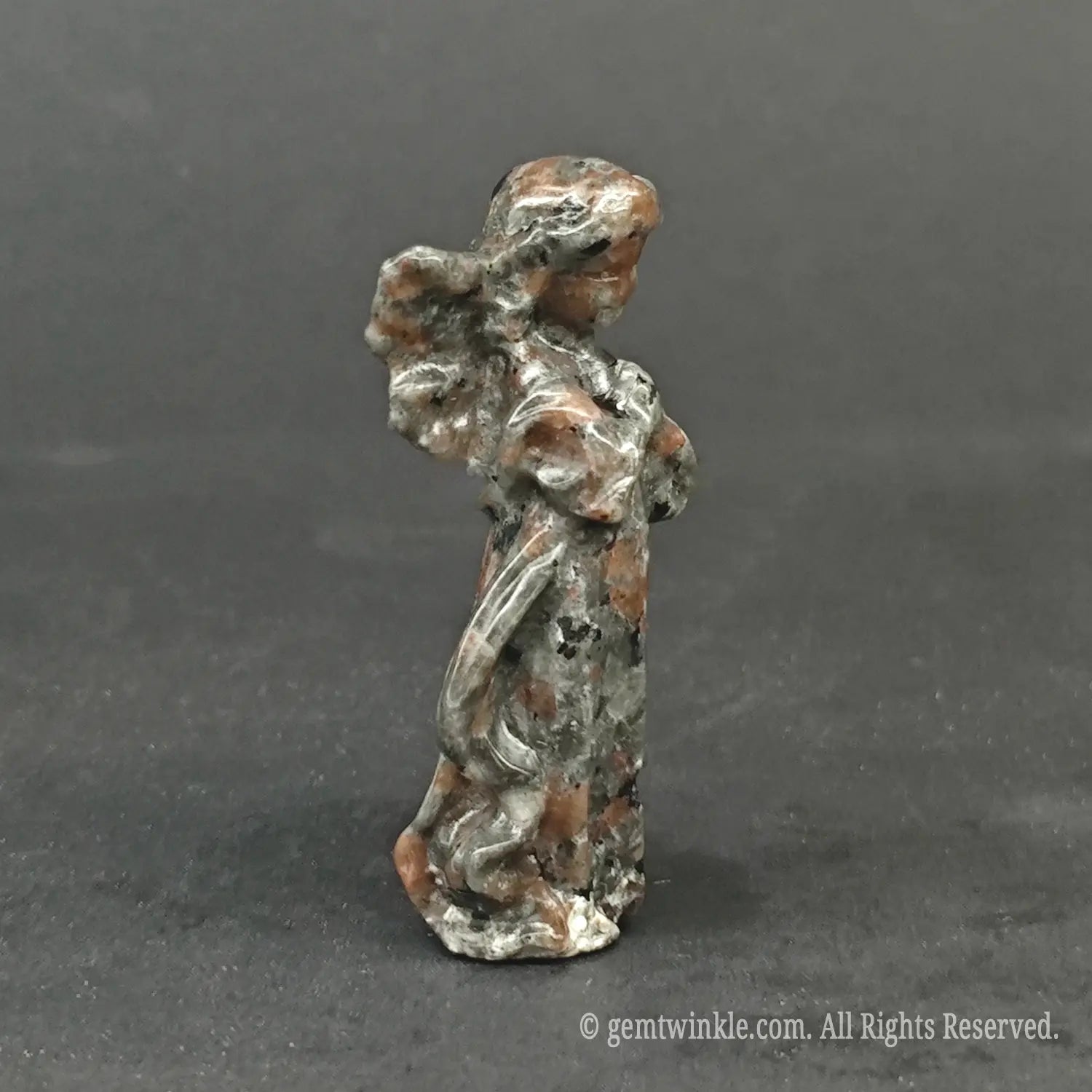 Hand holding a natural mottled granite guardian angel carving to showcase actual physical sizes and earthy stone finish for wholesale buyers