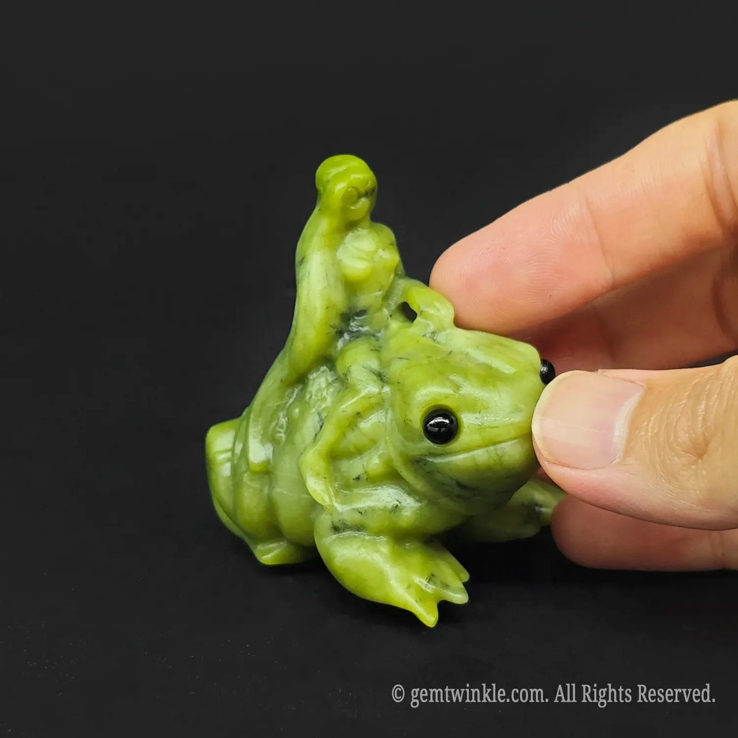 Hand holding a six centimeter serpentine nymph frog figurine to show the actual size scale for crystal wholesale buyers
