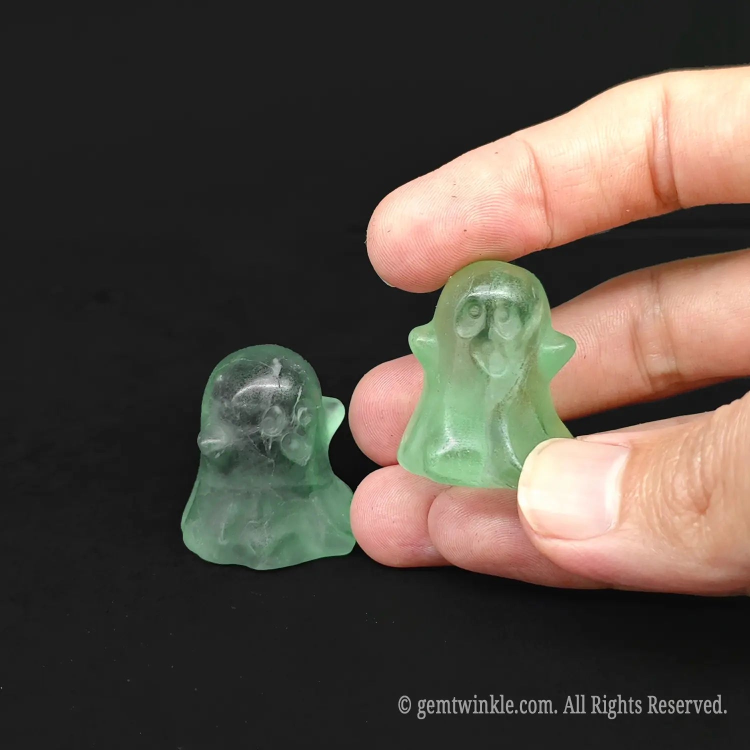 Hand holding a three centimeter green fluorite pocket ghost figurine to showcase its transparent clarity and size scale for wholesale buyers