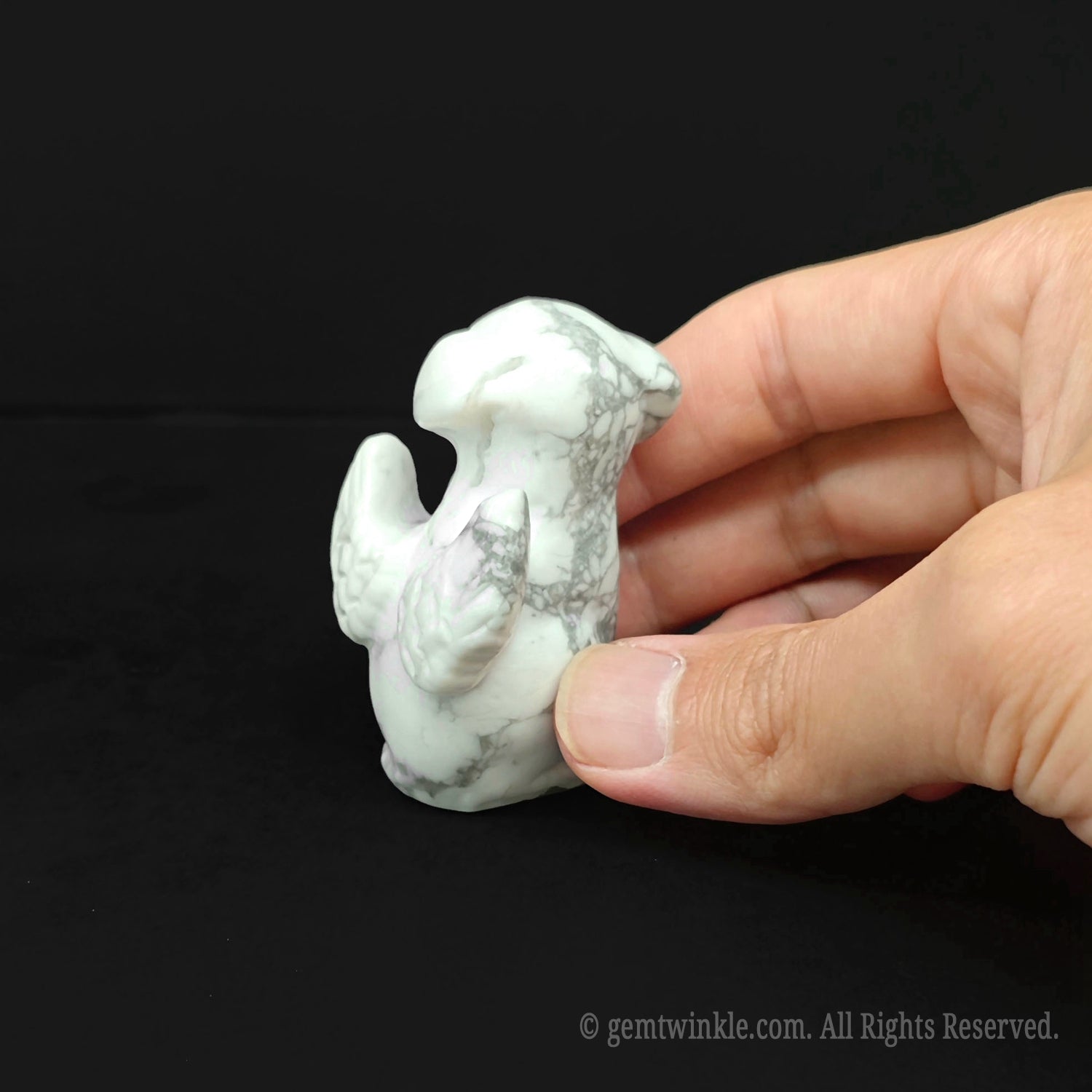 Back view of the hand sculpted white howlite puppy figurine showing carved angel wings detailed feathers