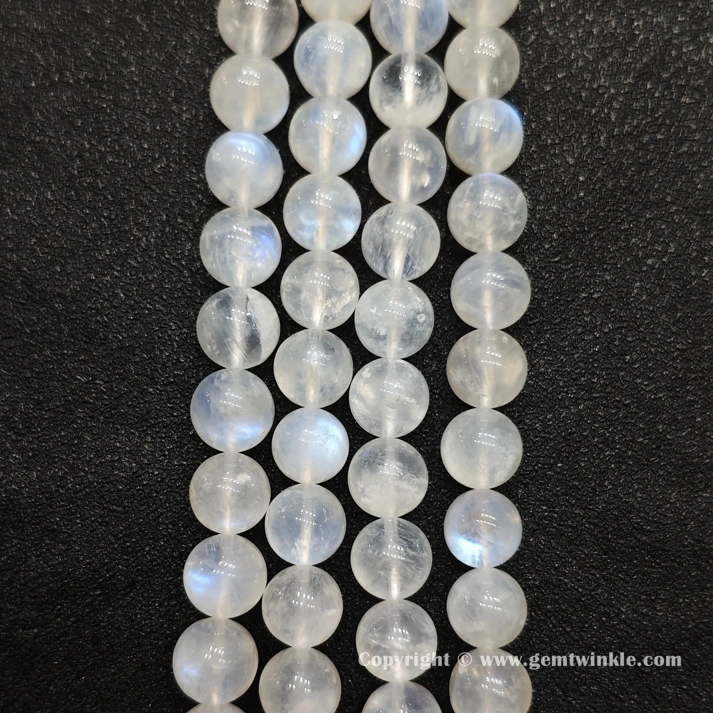 Perspective view of ice fractured blue flash moonstone round beads displaying polished surface across sizes