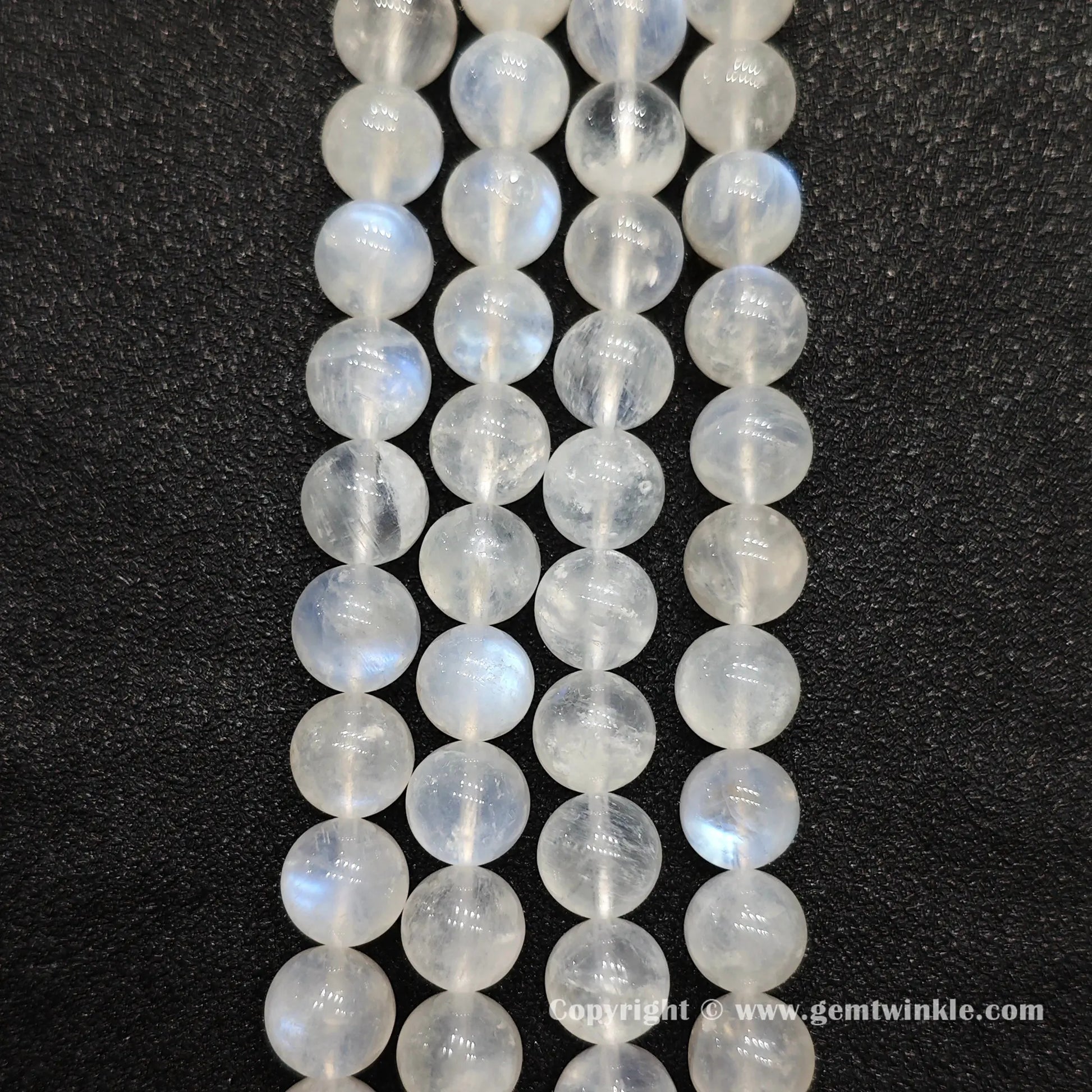 Perspective view of ice fractured blue flash moonstone round beads displaying polished surface across sizes