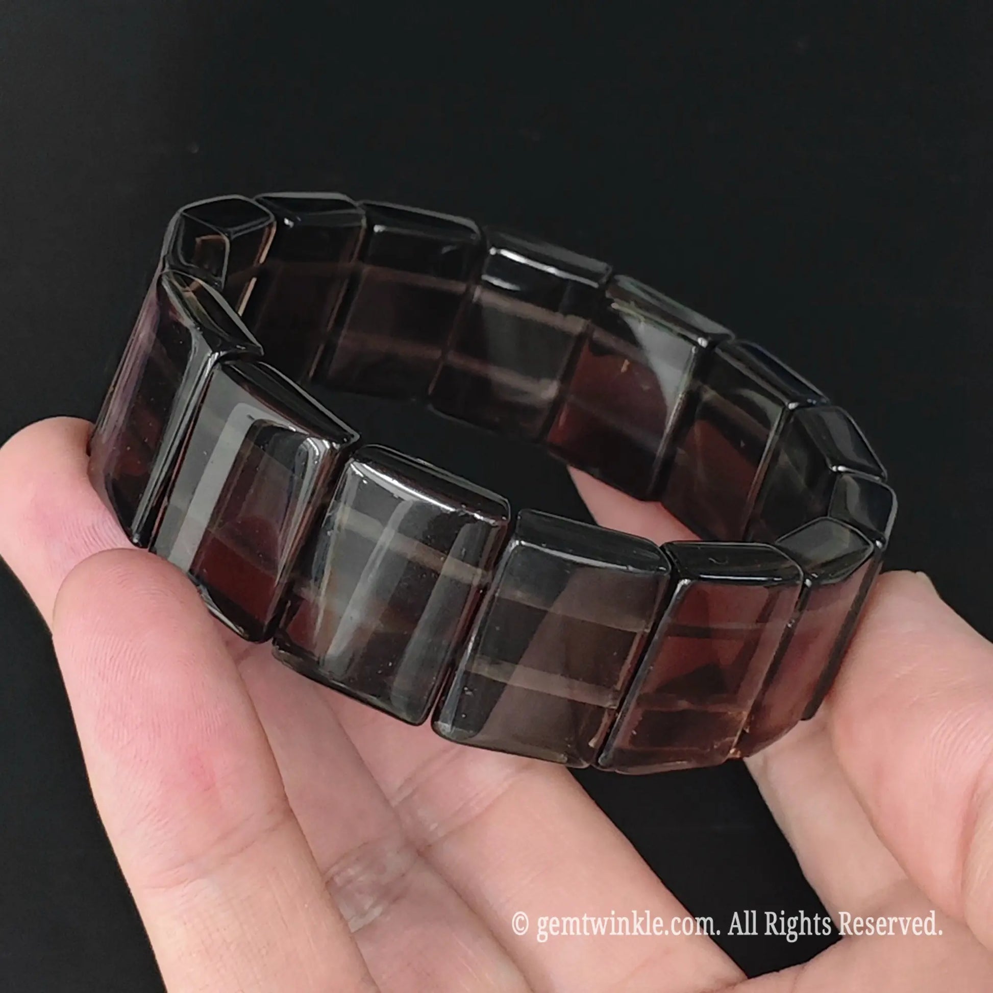 Overview of ice obsidian geometric rectangle plate bracelet resting in hand showing uniform plate bead alignment