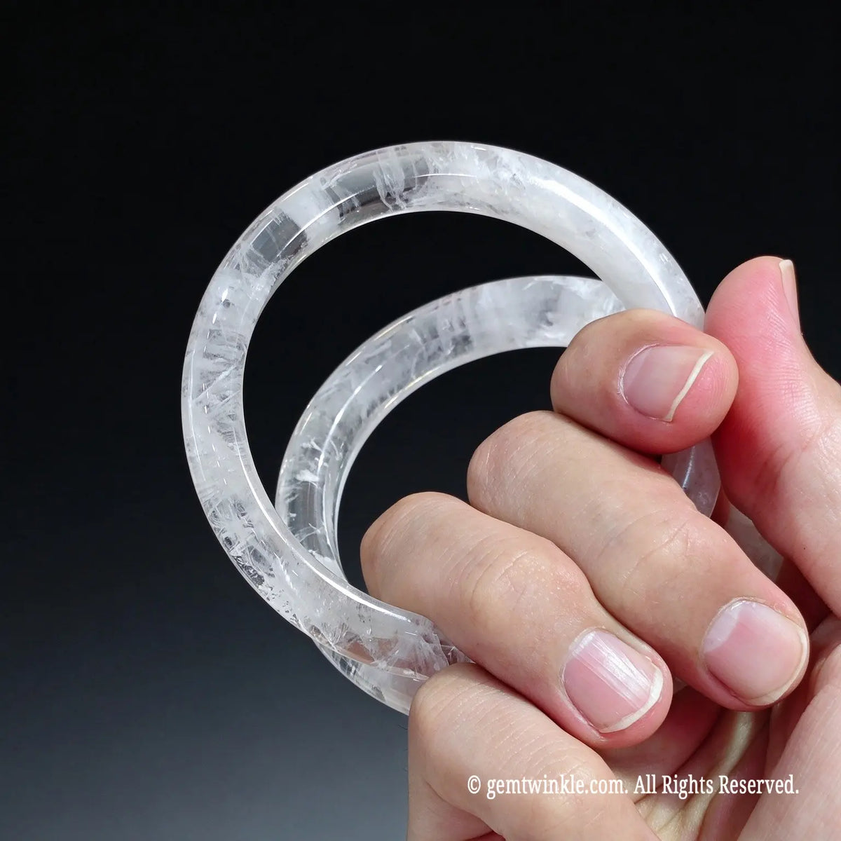 Full view of an icy white snowflake lodolite wristband held in hand displaying high gloss vitreous finish