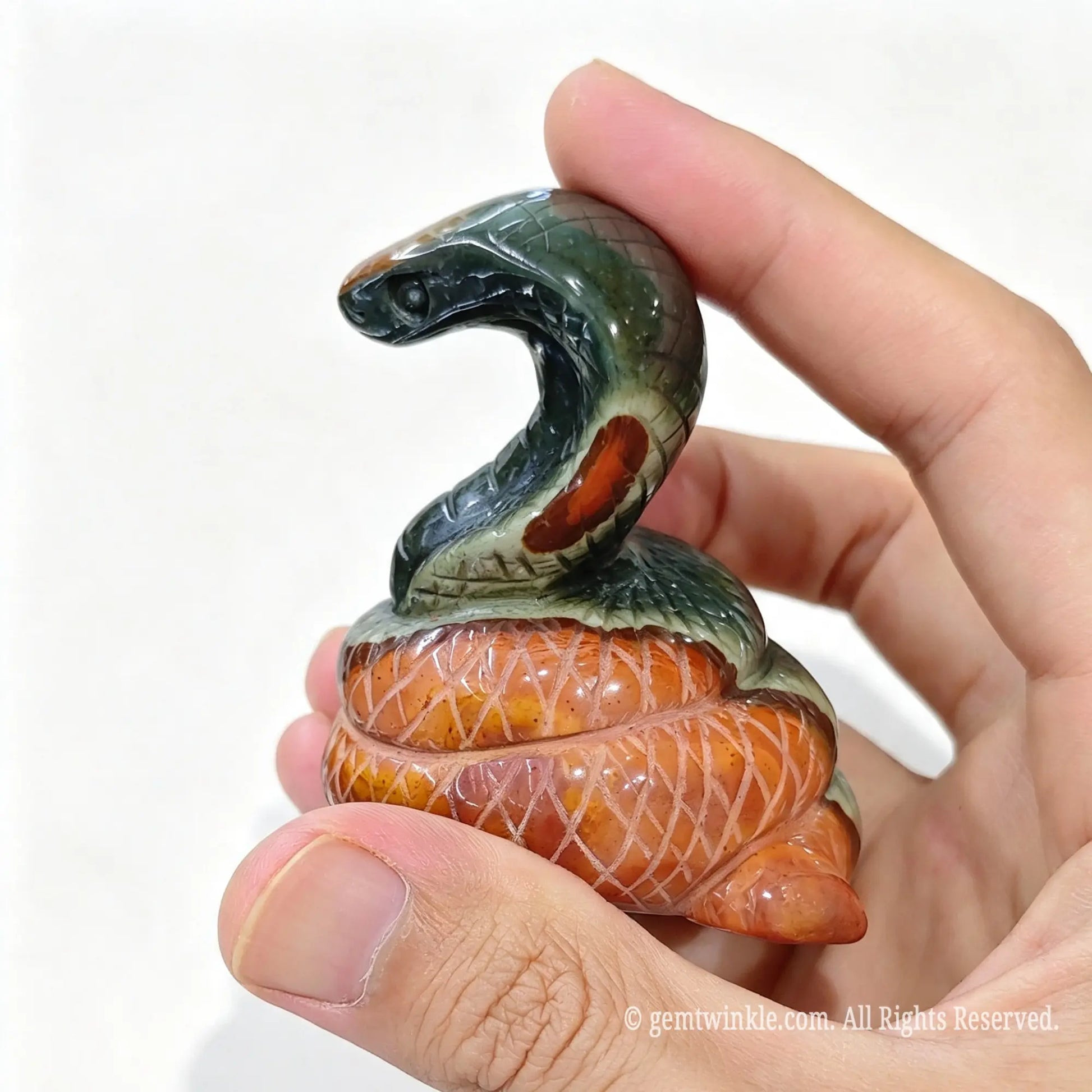 Side view of ocean jasper snake sculpture held in hand showing detailed carved body scales and upright hood