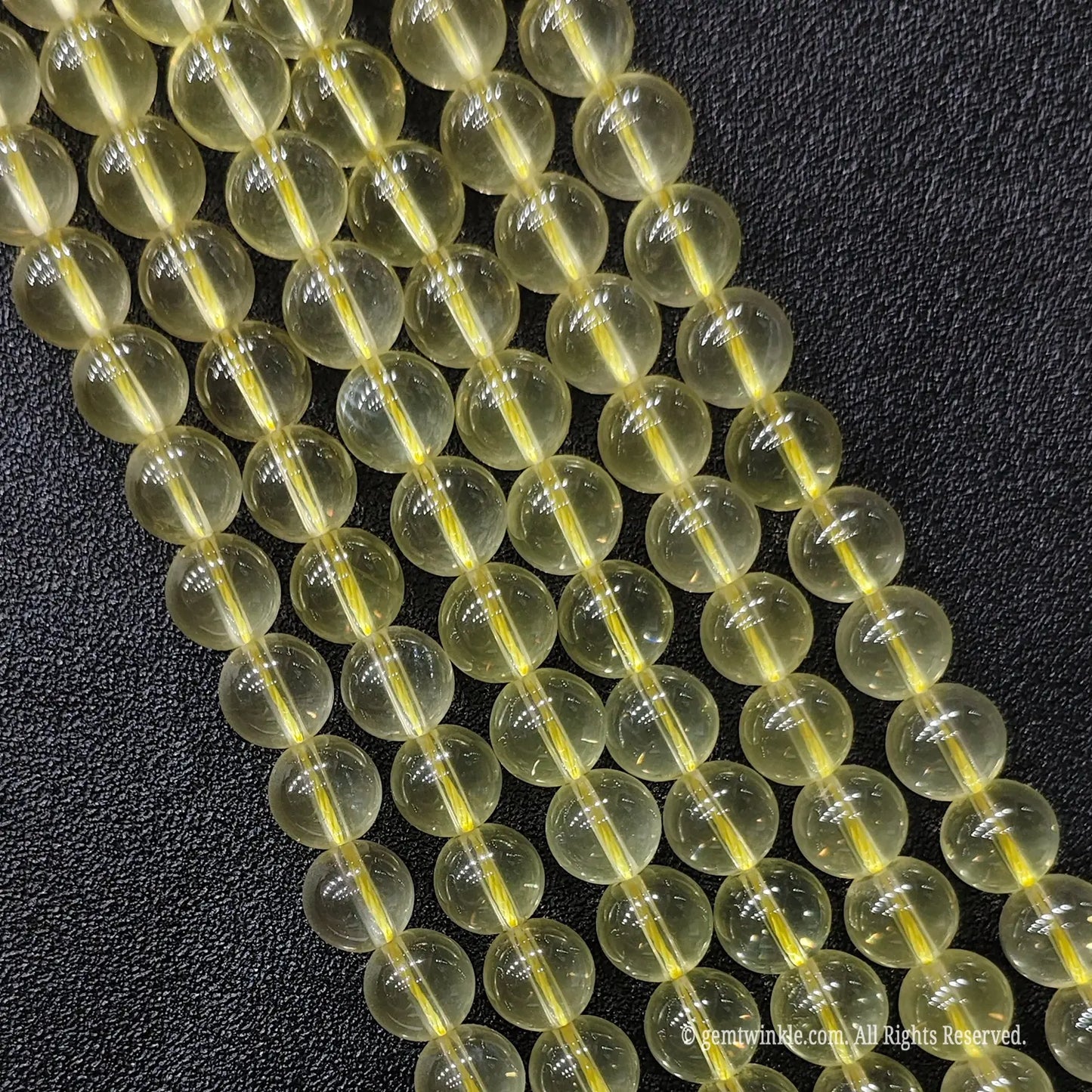 Close up of B plus grade semi translucent jelly like lemon yellow quartz gemstone beads displaying rich oily luster