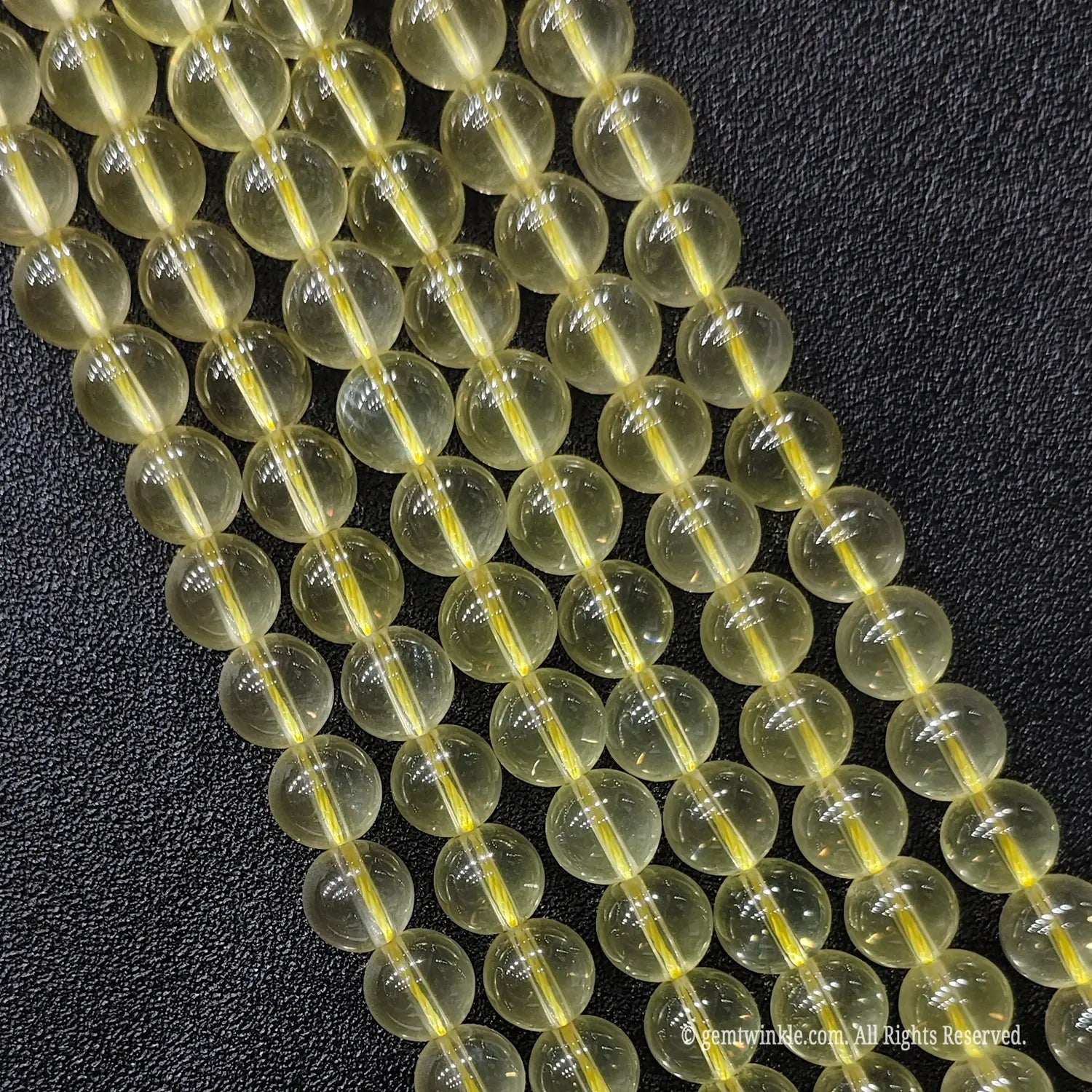 Close up of B plus grade semi translucent jelly like lemon yellow quartz gemstone beads displaying rich oily luster