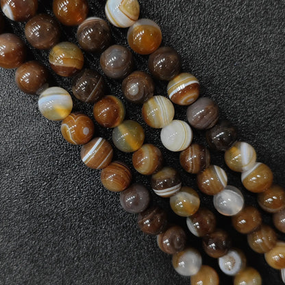 jewelry making supplies bulk showing polished glossy round dyed brown striped agate loose strands in 6mm to 12mm sizes on a dark background in image_77141c.jpg