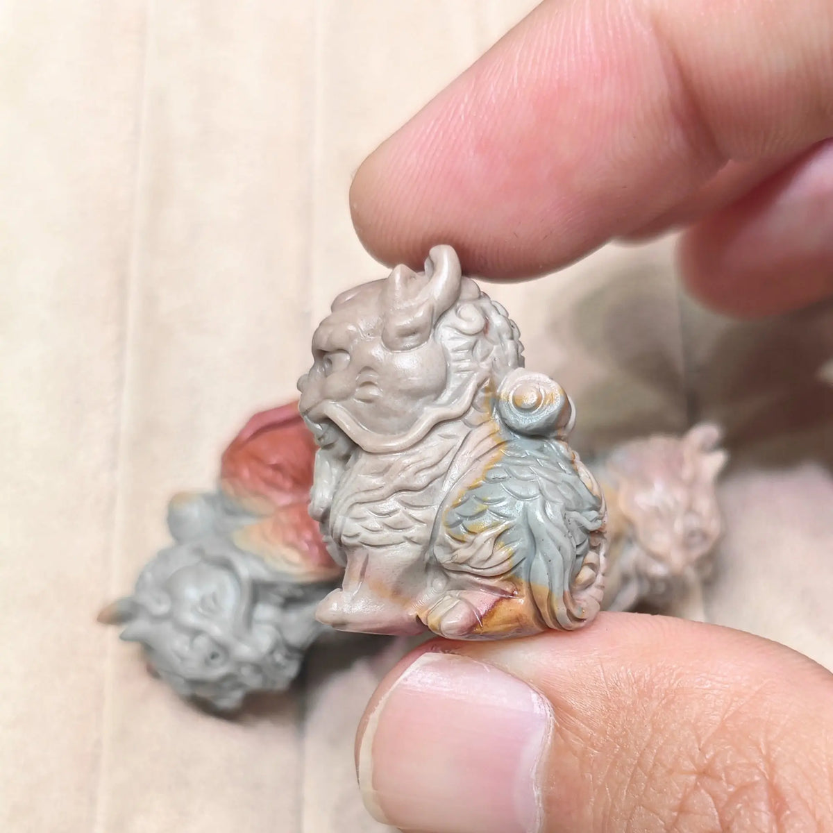 Three-quarter angle view of a small carved Kirin figurine showing detailed head and body scale carving in natural mineral stone