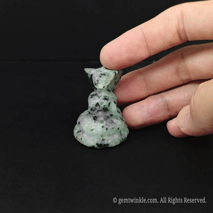 A tactile green and black speckled natural stone cobra skull figurine showing organic spotted textures