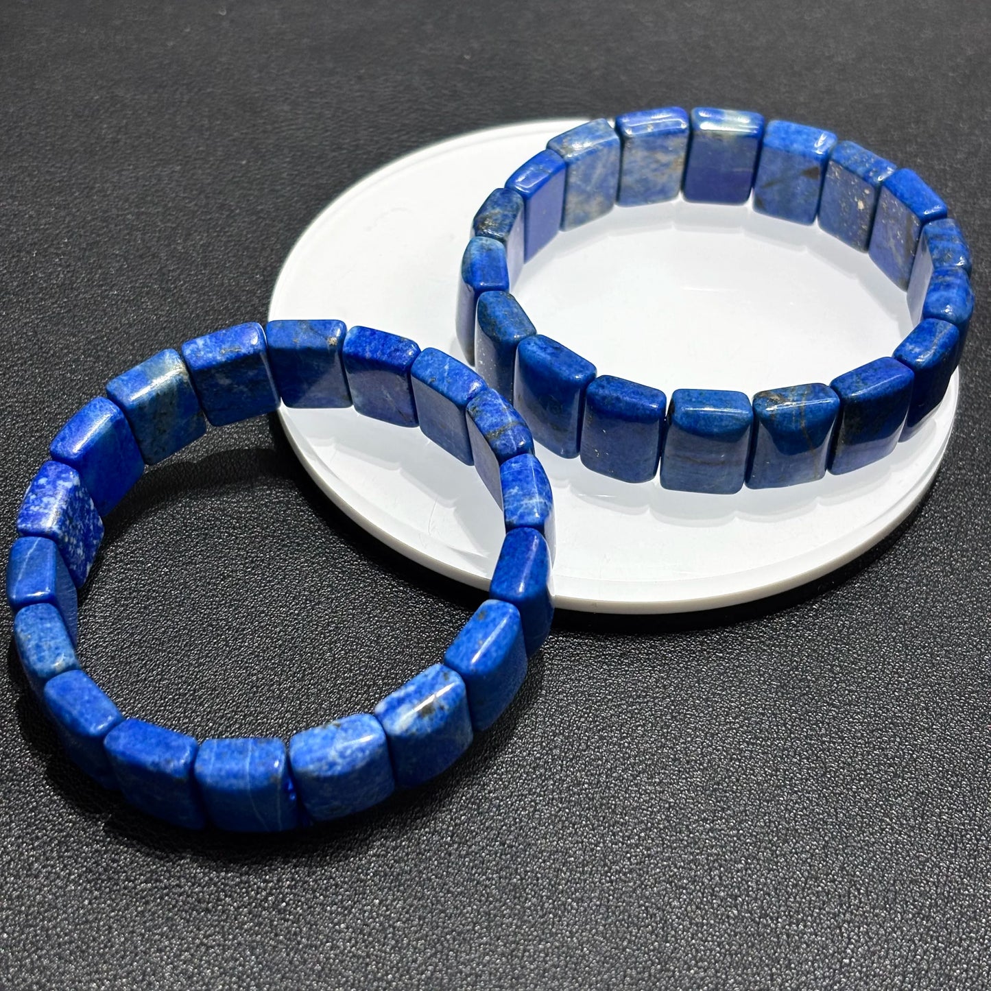 Two lapis lazuli bamboo bracelets stacked together on a white plate, ideal for layering and creating a bold fashion statement.