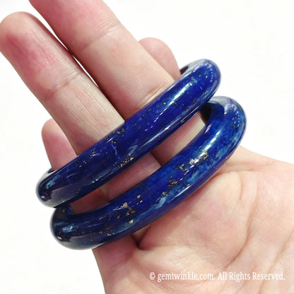 Stacked natural lapis lazuli gemstone bangles resting on palm showing classic circular shape and polished surface
