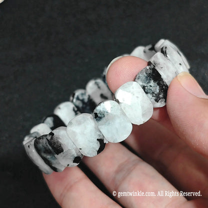 Angled view of a faceted rectangular moonstone bracelet highlighting its surface cut and blue flash