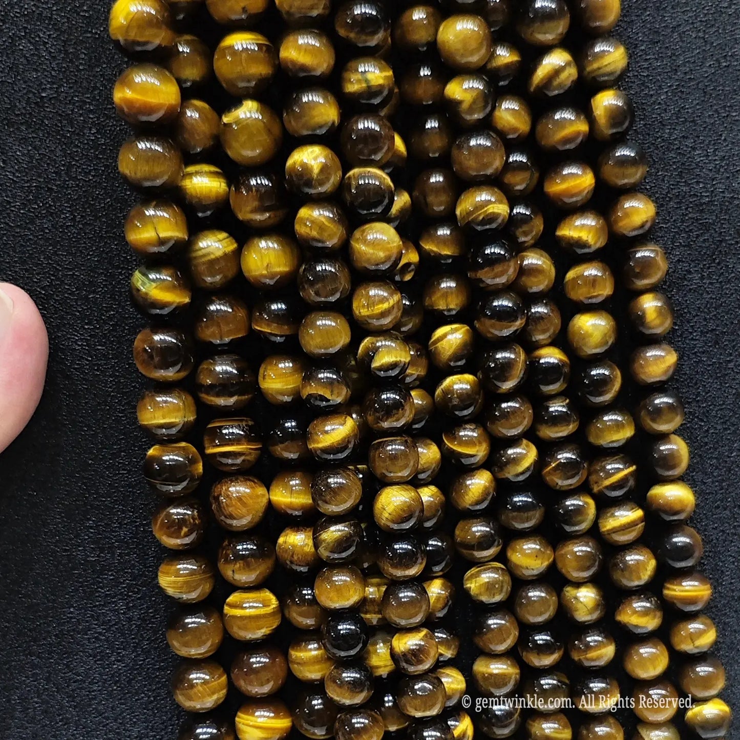 Assorted B plus grade 4mm to 20mm yellow tigers eye round beads on black background