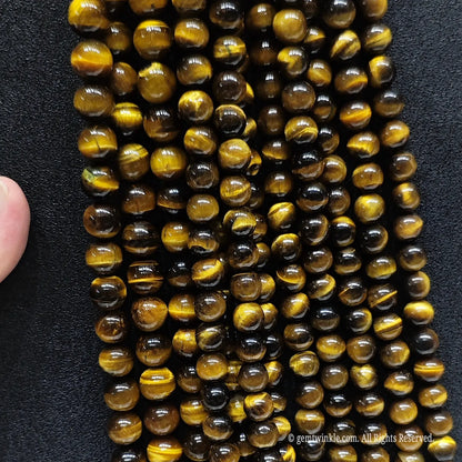 Assorted B plus grade 4mm to 20mm yellow tigers eye round beads on black background