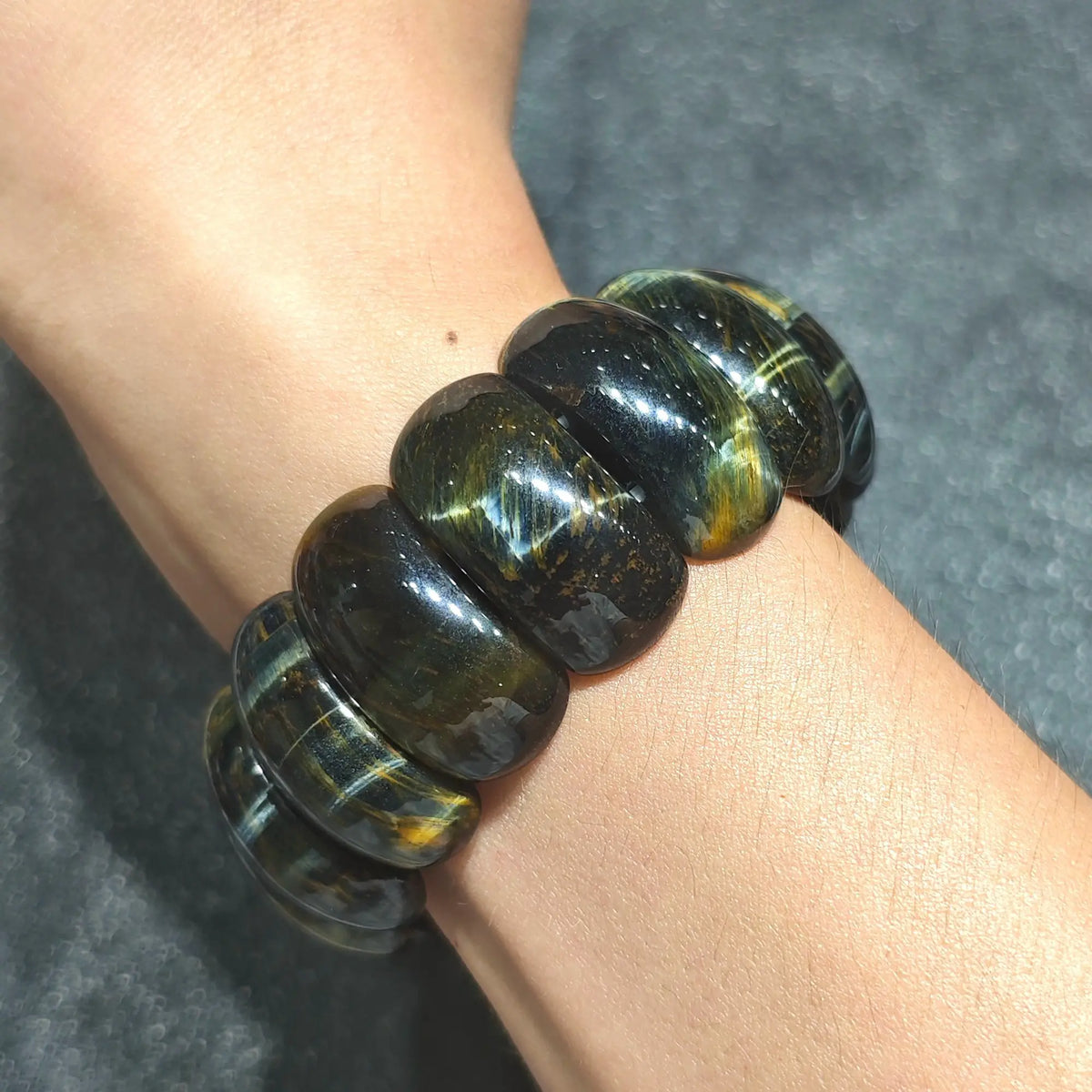 wrist shot of a single large natural tiger eye barrel bead stretch bracelet showing fit and bold statement profile