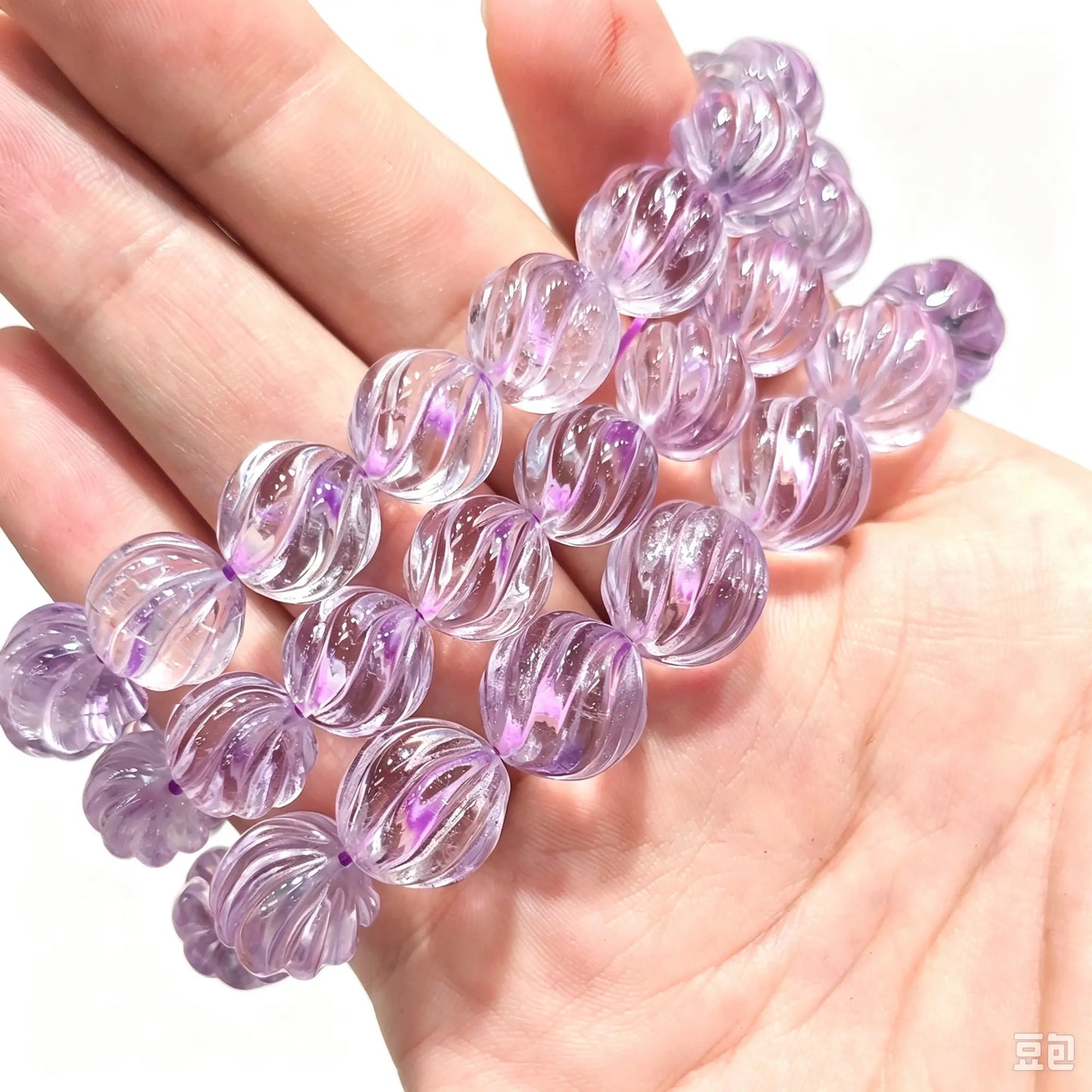 Main handheld view of light purple lavender amethyst carved pumpkin bead stretch bracelets showing glossy spiral fluted grooves