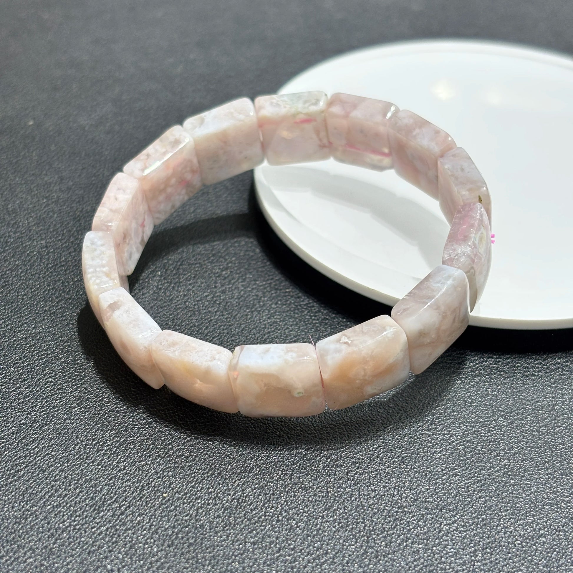 Layered flower agate bracelets worn with a white fur coat sleeve.