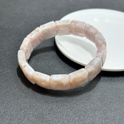 Layered flower agate bracelets worn with a white fur coat sleeve.