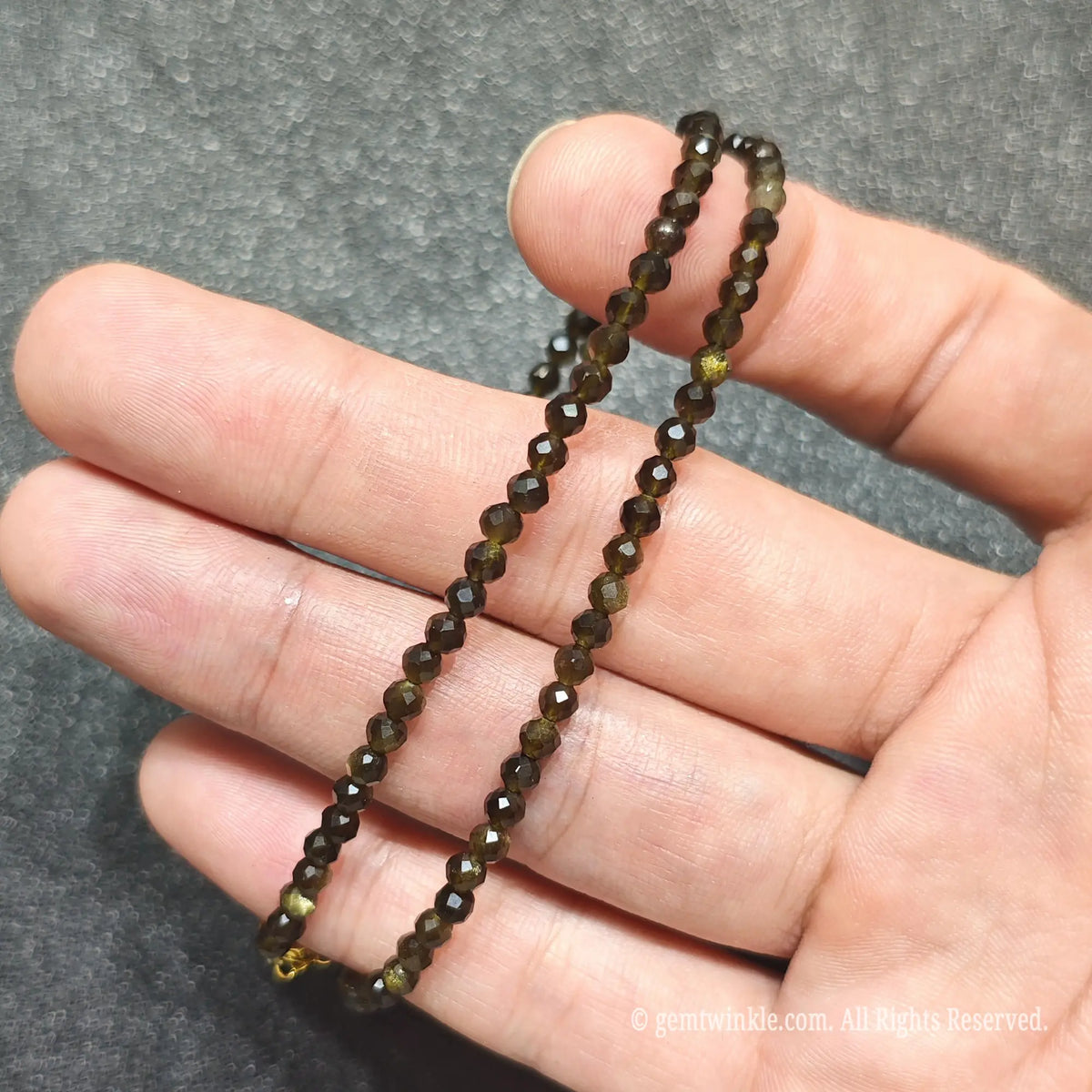 Coiled 3mm faceted Gold Sheen Obsidian necklace held across fingers suited for boutique reseller displays
