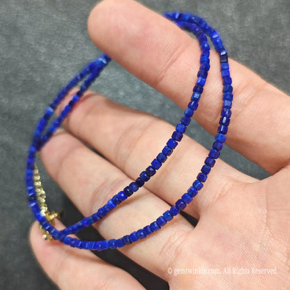 Coiled 2.5mm geometric cube cut Lapis Lazuli necklace held across fingers suited for boutique store displays