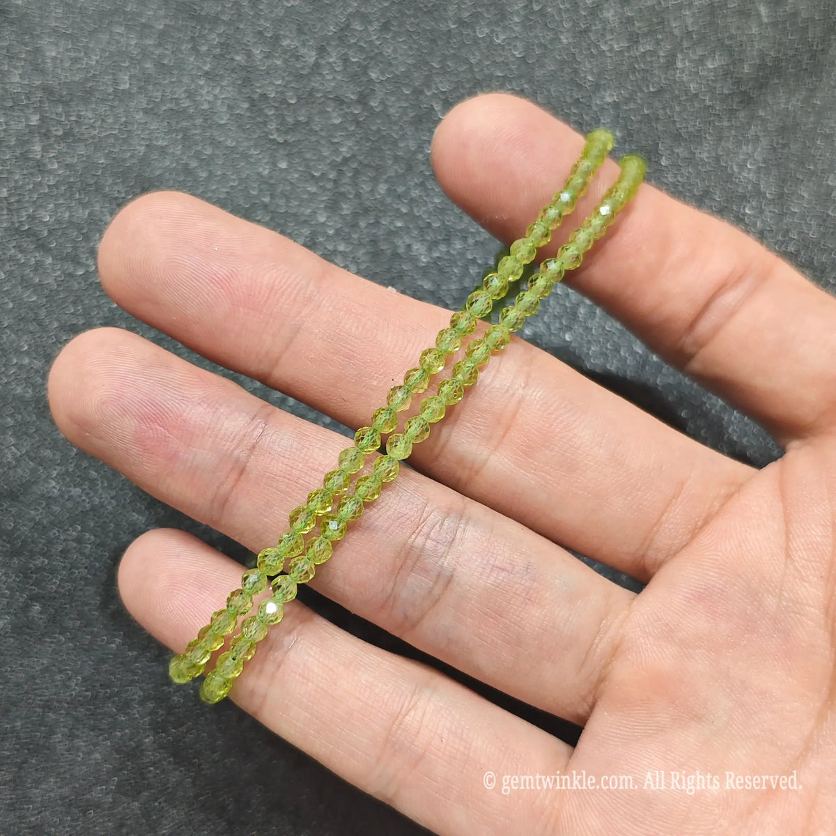 Coiled 3mm faceted peridot gemstone necklace held across fingers suited for women stackable neckwear styles