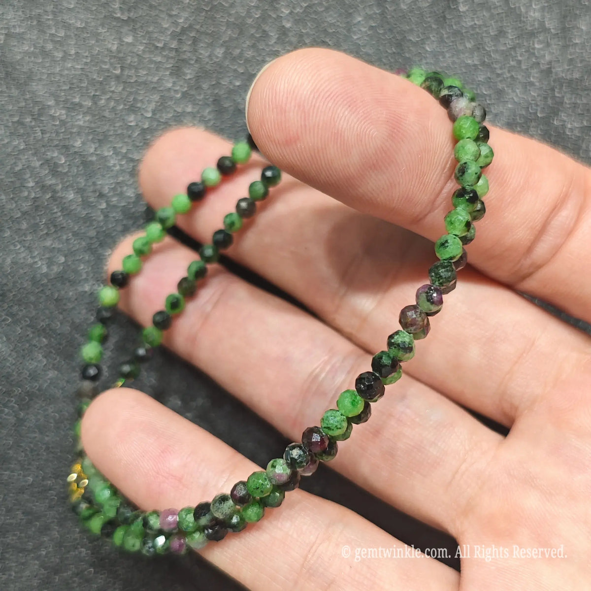 Coiled 3mm faceted Ruby in Zoisite necklace held across fingers suited for boutique reseller displays