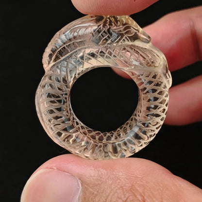 Lemon quartz carved snake ring held between fingers showing intricate scale details and pale yellow clarity