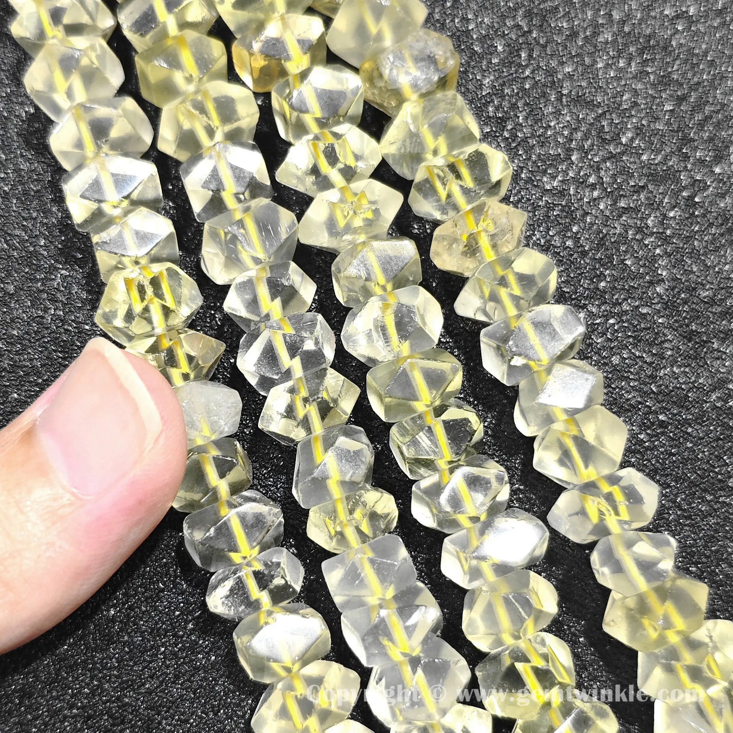 Hand holding 35cm strand of lemon quartz 10x6mm faceted column beads