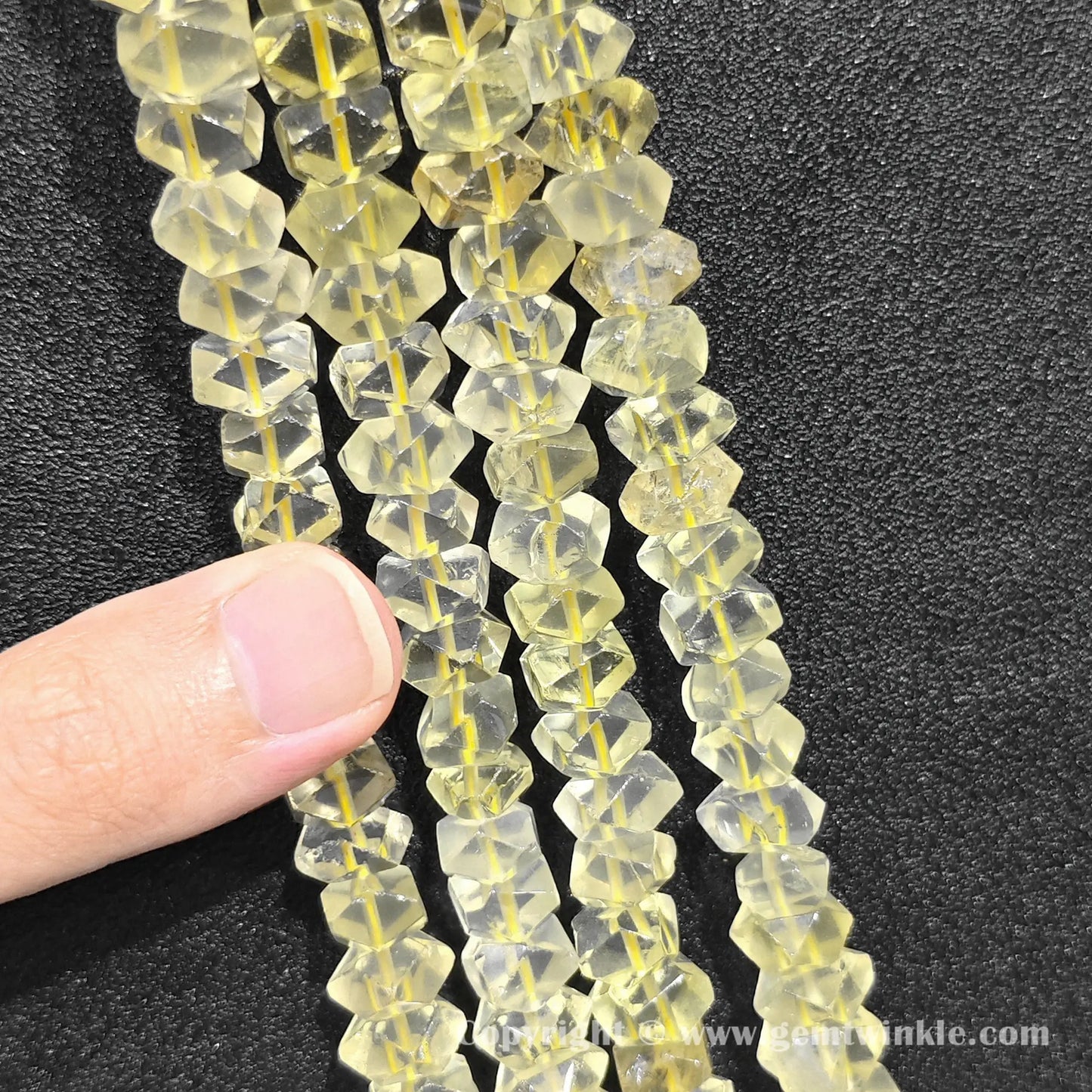 Vertical alignment of sunny lemon quartz prismatic cylinder column beads on dark surface