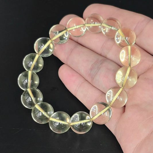 hand holding high clarity lemon quartz round beads stretch bracelet