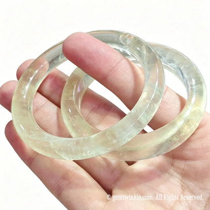 Stacked lemon yellow quartz bangles resting on palm showcasing bright translucent color tones
