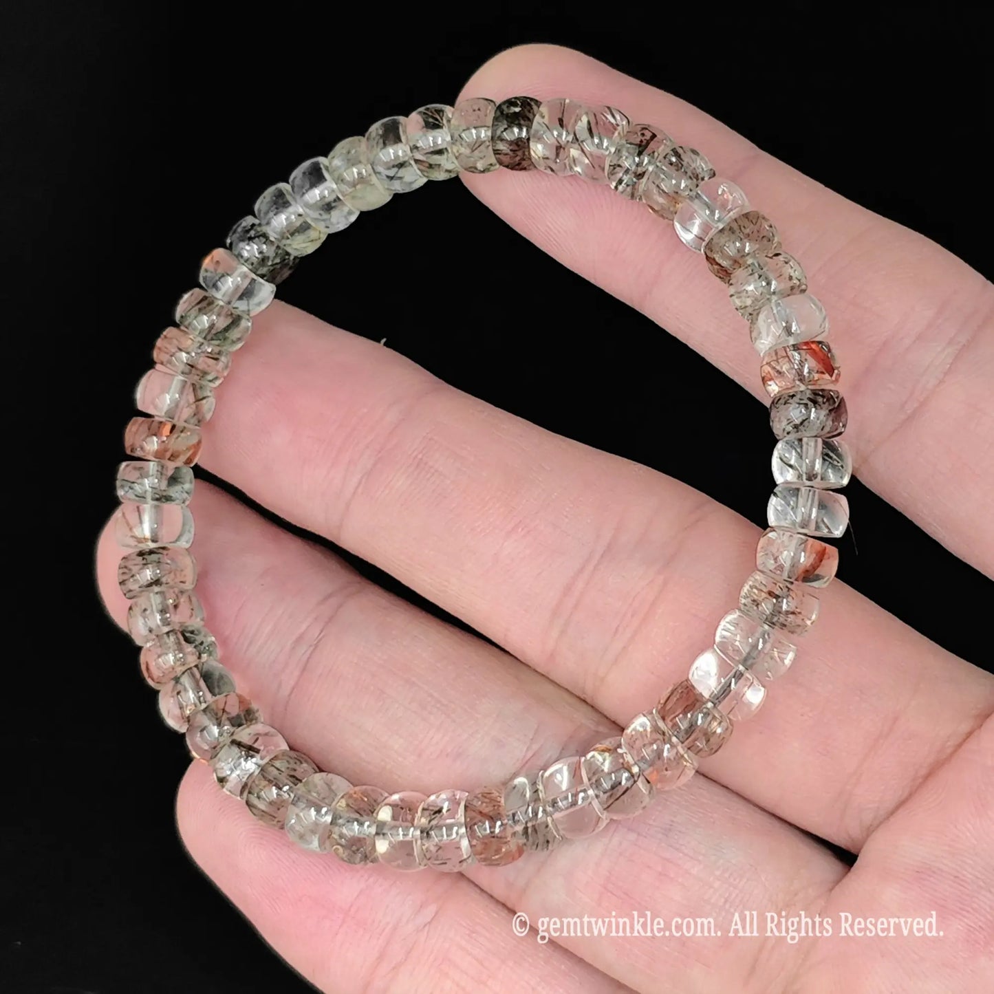 fingers holding translucent multi inclusion clear quartz disc bead stretch bangle