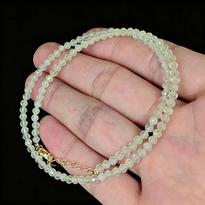 light green translucent prehnite faceted bead strand held in hand