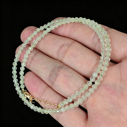 light green translucent prehnite faceted bead strand held in hand