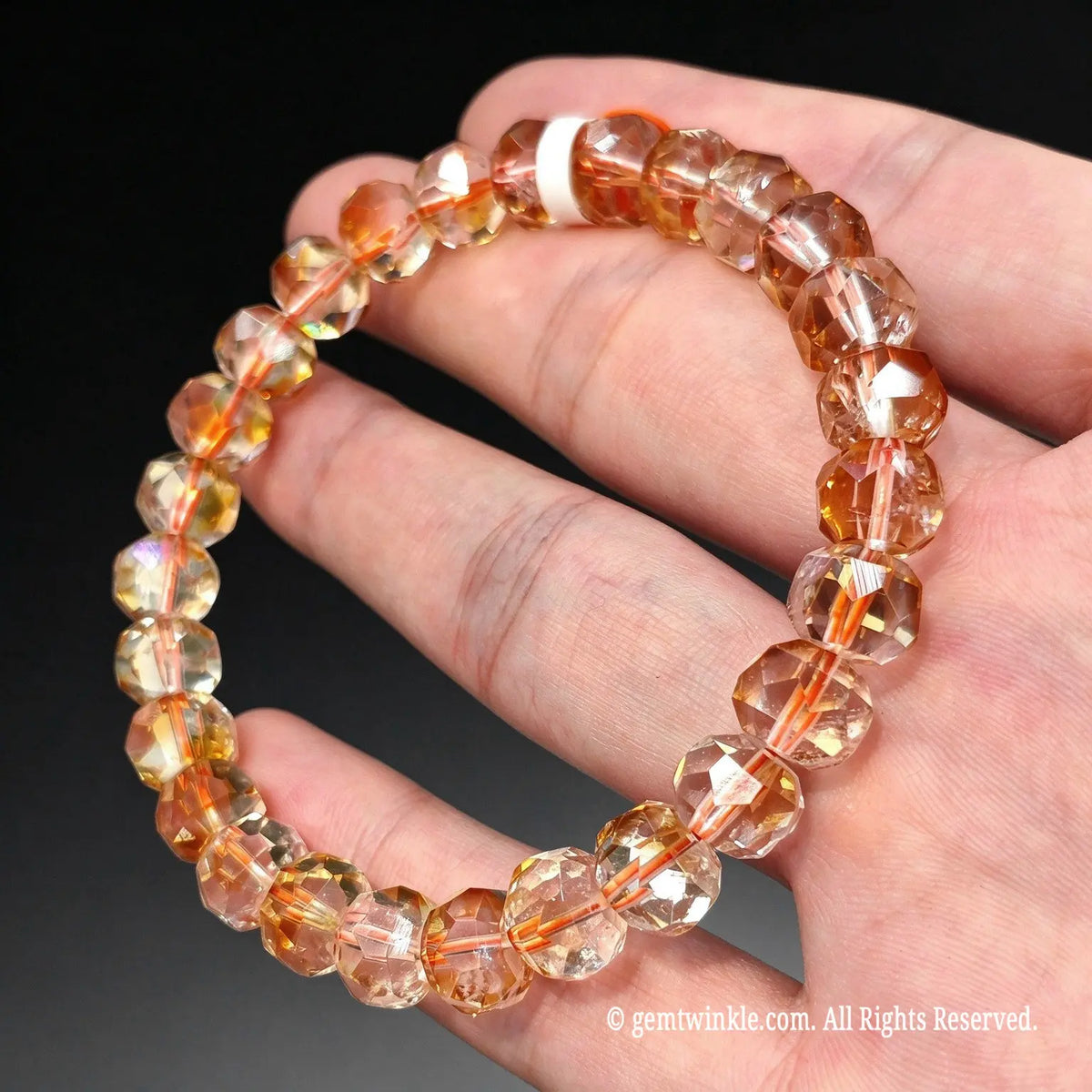 Side view of a light honey tower cut crystal bracelet worn on wrist against dark background