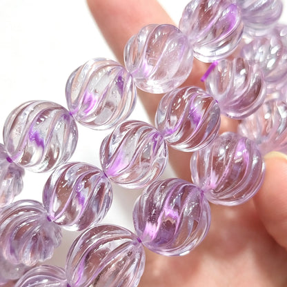 Close up view of translucent light lavender amethyst spiral carved melon beads strung on elastic line
