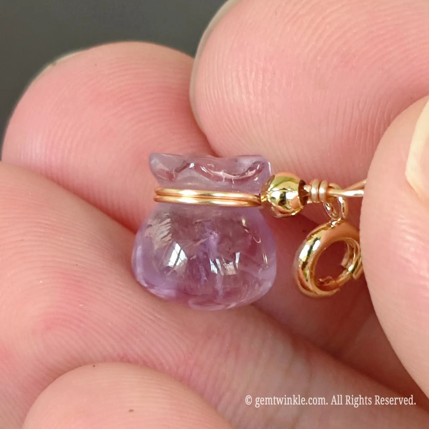 Light amethyst fortune bag charm close up view showing delicate gold wire wrapping around pouch collar