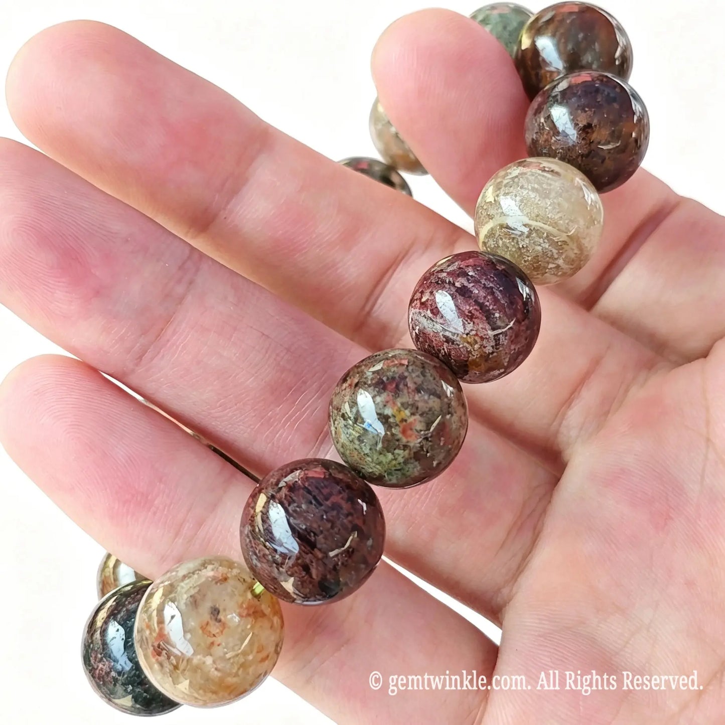 Side handheld view of natural multi-color garden quartz round bead stretch bracelet showing polished bead surface