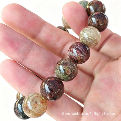 Side handheld view of natural multi-color garden quartz round bead stretch bracelet showing polished bead surface