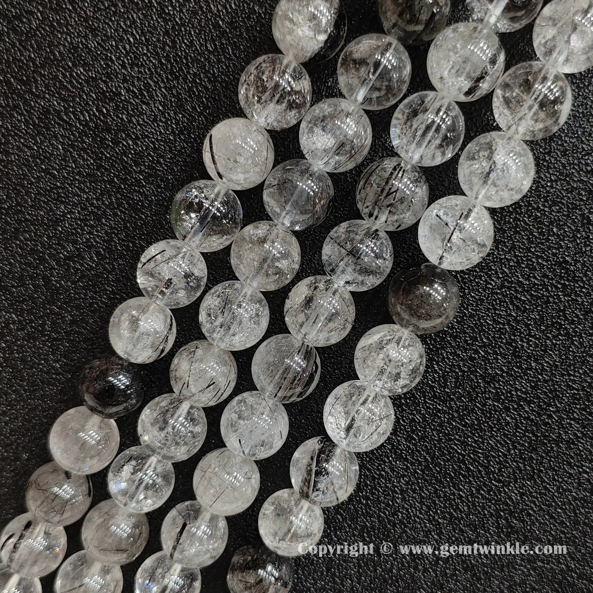 Four loose gemstone strands of genuine B grade black rutilated quartz beads showing clear matrix zones and natural internal crystalline lines