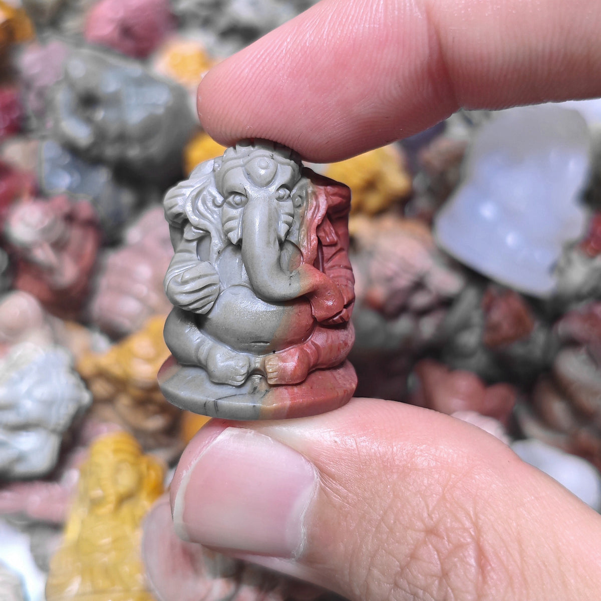 Side profile view of a mini Lord Ganesha statue held in hand displaying carved ear and trunk details