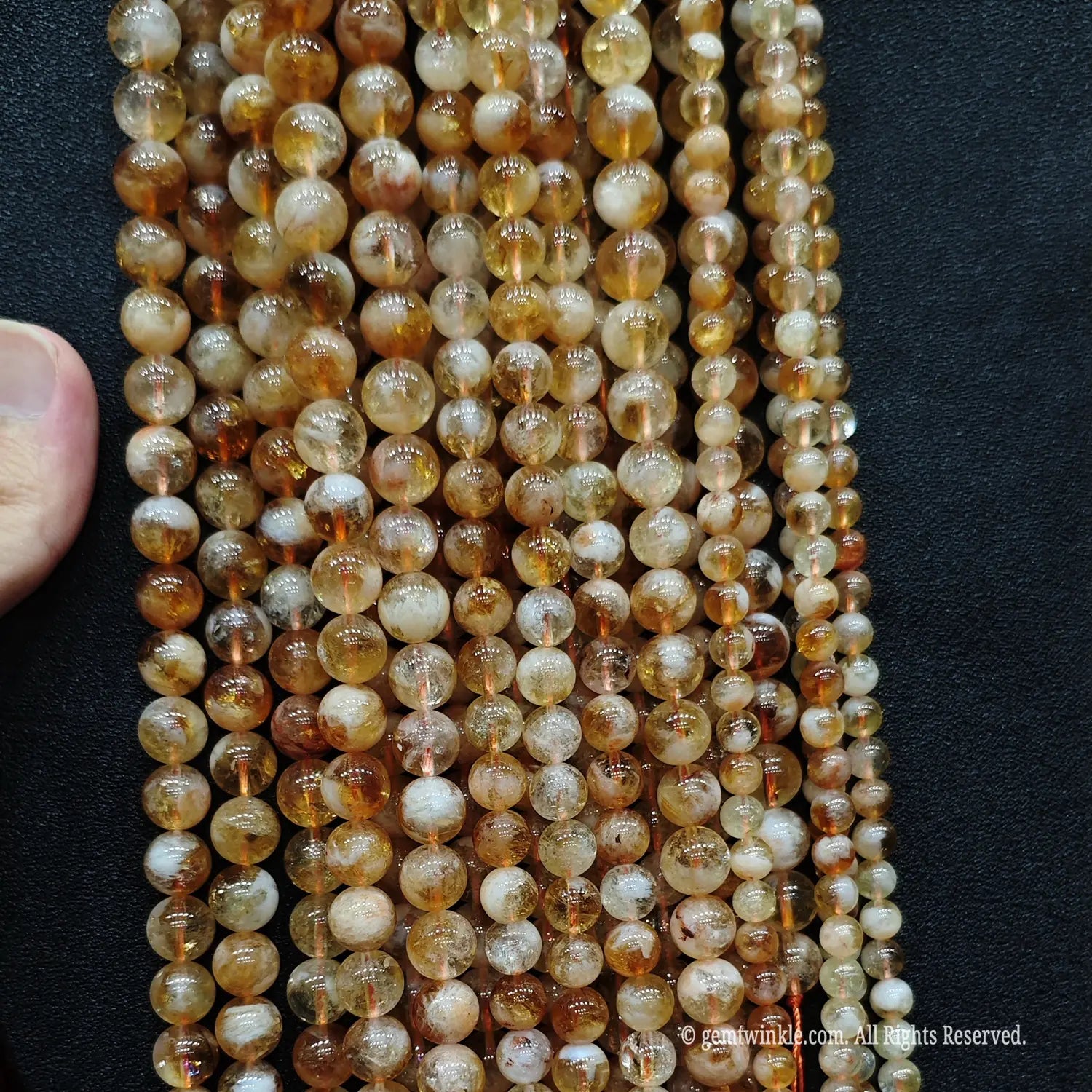 Vertical layout display of low cost golden tower phantom quartz bead strands showcasing an organic earthy appearance