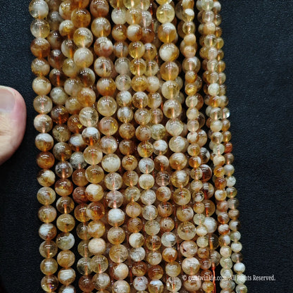 Vertical layout display of low cost golden tower phantom quartz bead strands showcasing an organic earthy appearance