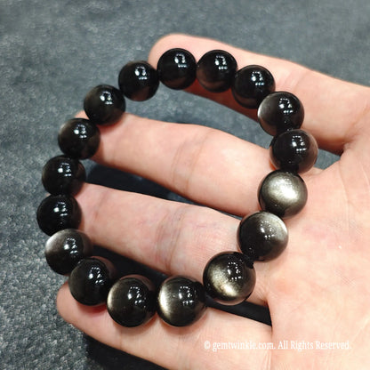 Premium grade 12mm silver obsidian beaded bangle under direct light highlighting razor sharp silver cat's eye line