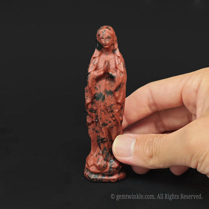 Close up of a 10cm mahogany obsidian Virgin Mary statue showing rich reddish brown and black patterns